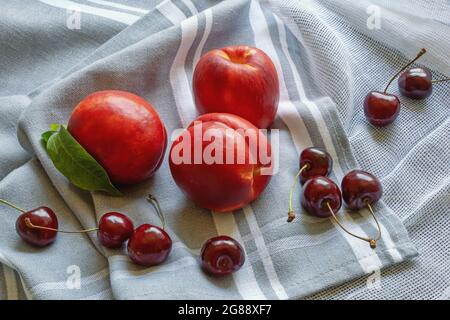 Red summer fruits. Fresh ripe cherries and nectarines on table Stock Photo