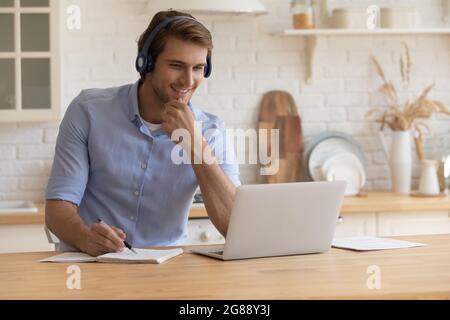 Confident young male in headset watching web course on pc Stock Photo