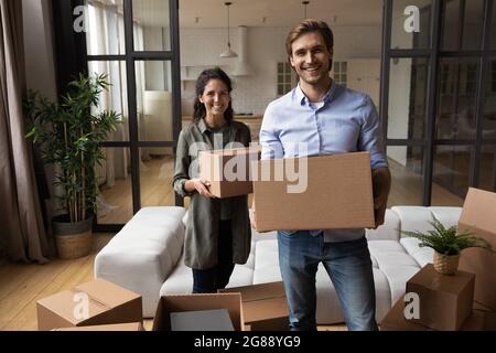 Young couple looking at camera holding packages in new home Stock Photo