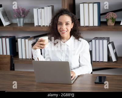 A beautiful Hispanic custom service worker smiles with confidence as she advises and assists customers in the workplace. Stock Photo