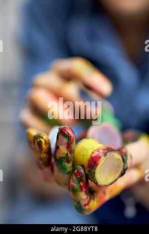 Close up shot of female hands holding colorful acrylic oil paints in jars Stock Photo