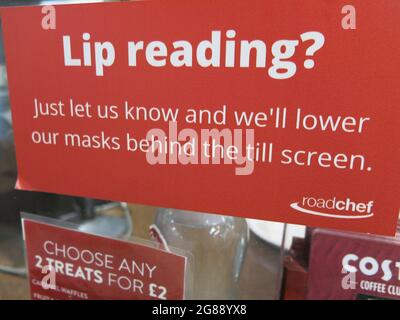 Lip reading? Signage on a till screen advising that face masks will be lowered if requested; improving accessibility at a motorway service station. Stock Photo