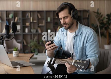 Distracted from practicing music happy young musician using smartphone. Stock Photo
