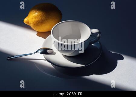Empty cup for tea or coffee with lemon, morning lights and shadows Stock Photo