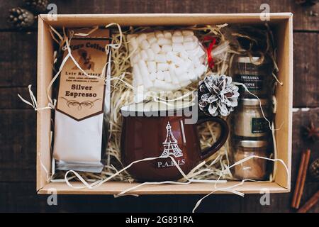 Lviv, Ukraine - December 1, 2017: Roasted Coffee, marshmallow, cup and spices on straw in gift box on wood. Top view. Stylish gift box for christmas,n Stock Photo