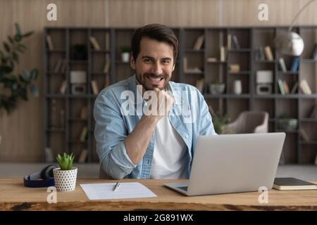 Happy millennial businessman looking at camera, posing in modern office. Stock Photo