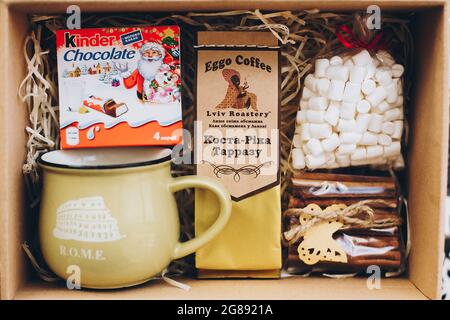 Lviv, Ukraine - December 1, 2017: Roasted Coffee, marshmallow, cup, kinder and cinnamon on straw in gift box. Top view. Stylish gift box for christmas Stock Photo