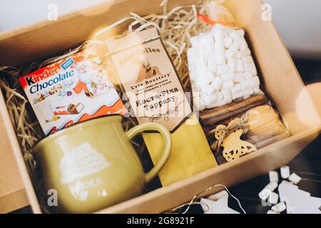 Lviv, Ukraine - December 1, 2017: Roasted Coffee, marshmallow, cup, kinder and cinnamon on straw in gift box. Stylish gift box for christmas,new year, Stock Photo