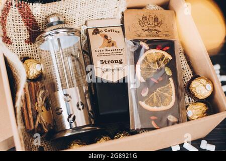 Lviv, Ukraine - December 1, 2017: Roasted Coffee, french press and chocolate candy on straw in lights. Stylish coffee gift box for christmas, new year Stock Photo