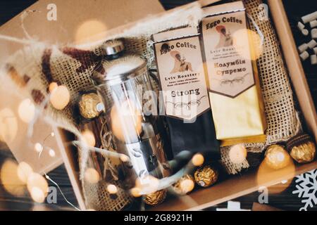 Lviv, Ukraine - December 1, 2017: Roasted Coffee, french press and chocolate candy on straw in lights. Stylish coffee gift box for christmas, new year Stock Photo