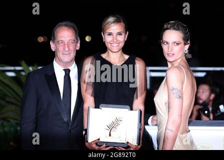 Cannes, France. 17th July, 2021. French director Julia Ducournau (C), French actor Vincent Lindon (L) and French actress Agathe Rousselle, who won the Palme d'Or award for the film 'Titane', pose during a photocall at the 74th Cannes Film Festival in Cannes, France, July 17, 2021. The 74th Cannes Film Festival concluded here on Saturday. Credit: Gao Jing/Xinhua/Alamy Live News Stock Photo