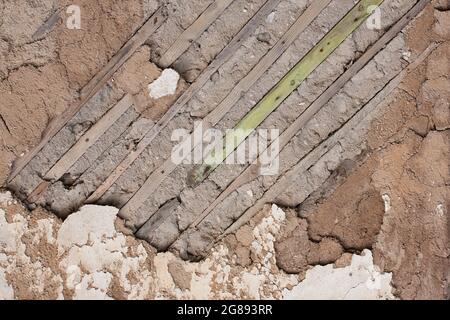 Fragment of an old destroyed wall with fallen off plaster and wooden lath in abandoned house. Close-up Stock Photo