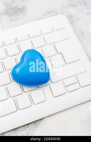 Blue heart + white Qwerty keyboard for Blue Monday, feeling gloomy / dispirited, poor office morale, being dumped online, Covid lockdown mental blues. Stock Photo