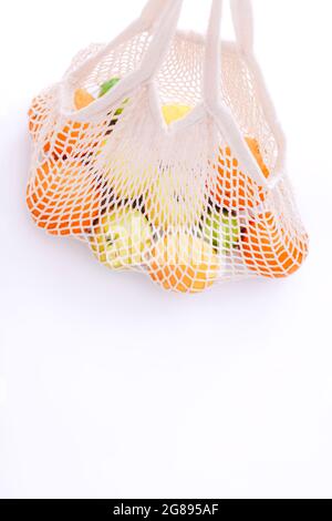 Mesh shopping bag with fresh fruits on white background. Zero waste, plastic free concept. Stock Photo