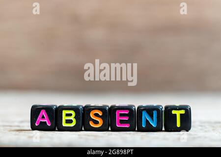 Black bead with color alphabet in word absent on wood background Stock Photo