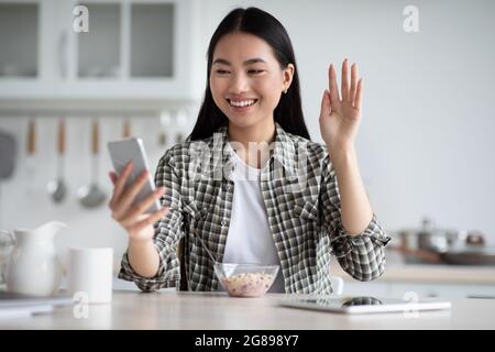 Happy asian woman having video chat during breakfast Stock Photo