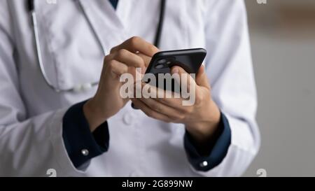 Hands of doctor in white coat using mobile phone Stock Photo