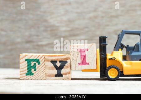 Toy forklift hold letter block I to complete word FYI (Abbreviation of For your information) on wood background Stock Photo