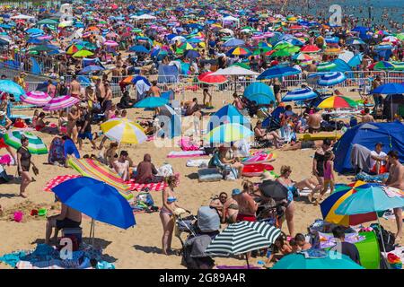 Bournemouth, Dorset UK. 18th July 2021. UK weather: hot sunny day at Bournemouth beach on the South Coast, as crowds flock to the seaside and sunseekers enjoy the sunshine in the heatwave. Beaches are packed with barely a spare space and car parks full.  Credit: Carolyn Jenkins/Alamy Live News