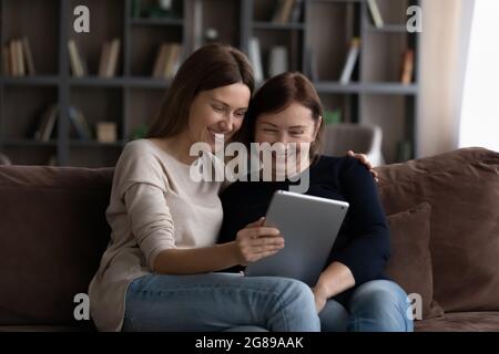 Happy grownup daughter showing content on tablet to mature mother Stock Photo