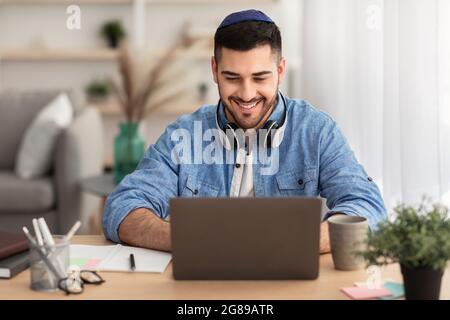 Smiling israeli man working on laptop at home Stock Photo