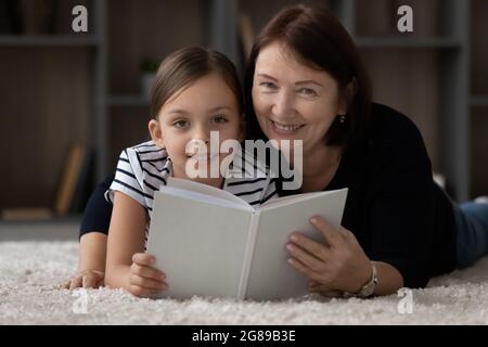Sweet child reading paper book with granny Stock Photo