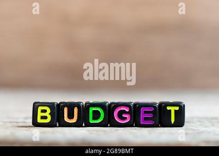 Black bead with color alphabet in word budget on wood background Stock Photo