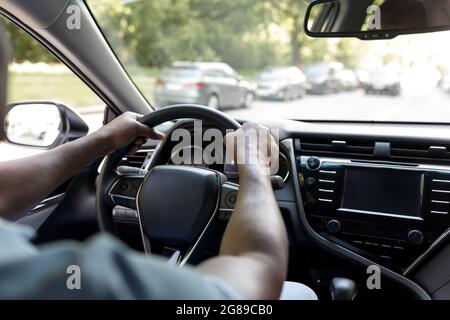 Cropped of black man driving luxury car, over shoulder shot Stock Photo