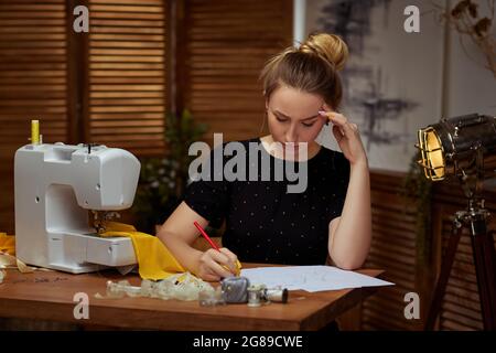 Beautiful young seamstress working on sewing machine Stock Photo