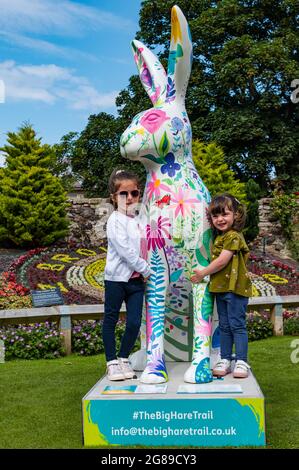 Two young girls with floral giant hare artwork sculpture, The Big Hare Trail event, Lodge Grounds park, North Berwick, East Lothian, Scotland, UK Stock Photo