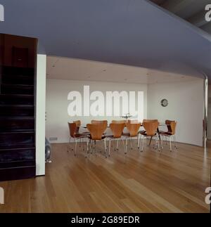 Large modern table with 12 chairs in empty architectural space. Stock Photo