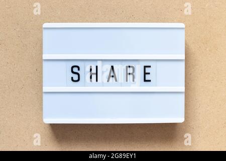 White lightbox with word share on wood background Stock Photo