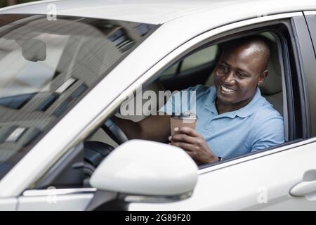 Relaxed black driver enjoying coffee break inside car Stock Photo
