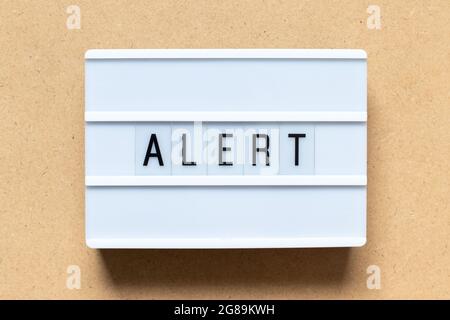 White lightbox with word alert on wood background Stock Photo