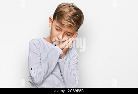 Little caucasian boy kid wearing casual clothes sleeping tired dreaming and posing with hands together while smiling with closed eyes. Stock Photo