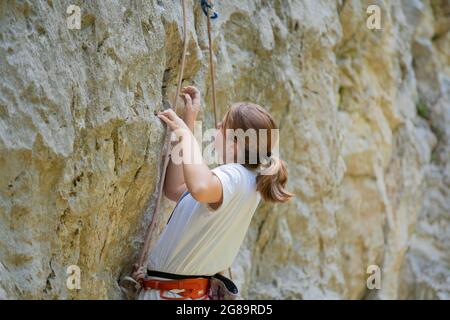 Teenage girl in a difficult rock climbing tour in the La Gola climbing area, Sarca Valley, Lake Garda mountains, Trentino Italy Stock Photo