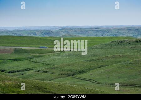 Vehicles travel south on Interstate 90 near Story, Wyoming. Trail on foreground hill is route of the old Bozeman Trail, a branch of the Oregon Trail. Stock Photo