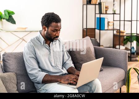Handsome black adult man working with computer laptop at home Stock Photo