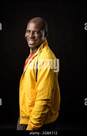 Side view of an African American man standing looking at camera and smiling  Stock Photo