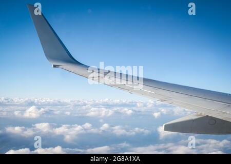 Flying above the clouds: airplane wing and cumulous clouds Stock Photo