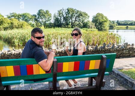 Dunmanway, West Cork, Ireland. 18th July, 2021. Temperatures hit the high 20's in Dunmanway, West Cork today. Met Eireann has forecast a mini-heatwave with high temperatures until late next week. Enjoying an ice-cream at Dunmanway Lake were Aiden and Aoibhin Kelly from Johnstown. Credit: AG News/Alamy Live News Stock Photo