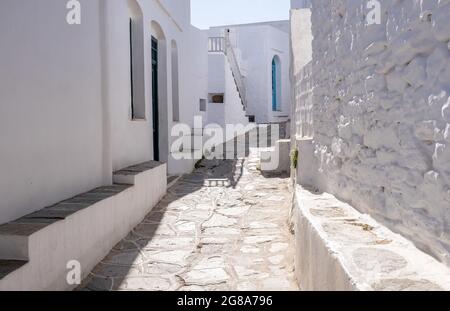 Sifnos island, Cyclades Greece. Traditional greek whitewashed stonewall buildings empty narrow cobblestone alley background sunny day. Destination sum Stock Photo
