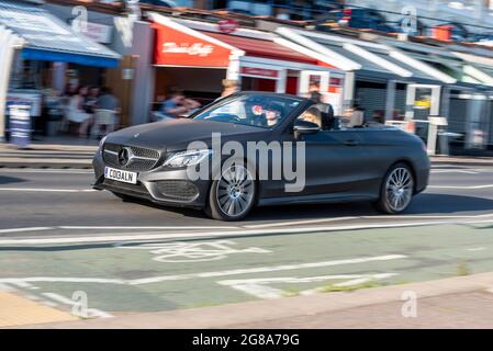 Matt black Mercedes car driving at speed along the seafront road at Southend on Sea, Essex, on a hot summer day passing Arches Cafes. 2017 Mercedes Stock Photo