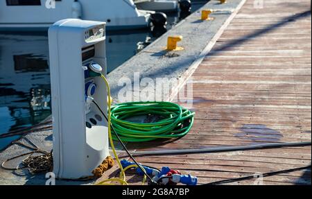 Greece. Charging electrical outlets for ships in harbour. Marina supply station, Electric power and water for moored vessels at dock, copy space. Myko Stock Photo