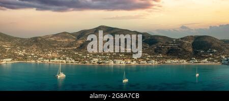 Sifnos island, Platis Gialos, Cyclades Greece. Panoramic view of traditional village colorful sunset on sky dark blue sea sandy beach. Moored boats su Stock Photo