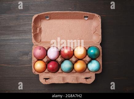Packaging with colored Easter eggs on wood table background. Flat lay. Stock Photo