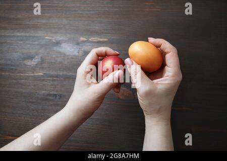 Easter eggs in female hands on wooden background. Stock Photo