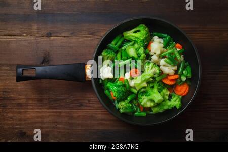 Fried vegetables in pan on wood table background. Flat lay. Stock Photo