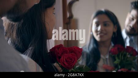 A man surprising his girlfriend with flowers at home Stock Photo