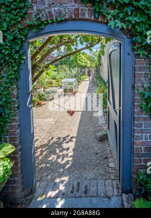 Looking through a wooden door into the walled garden in Corsley House in Corsley, Wiltshire, UK on 18 July 2021 Stock Photo